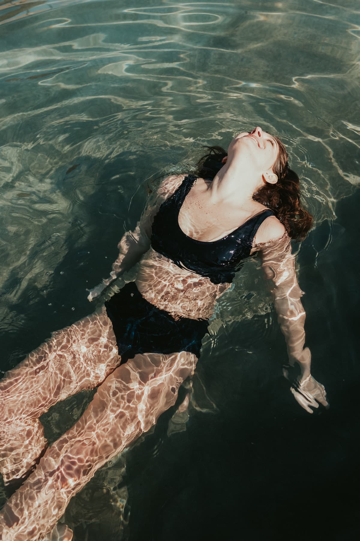 Modèle flottant en maillot dans une piscine bleue